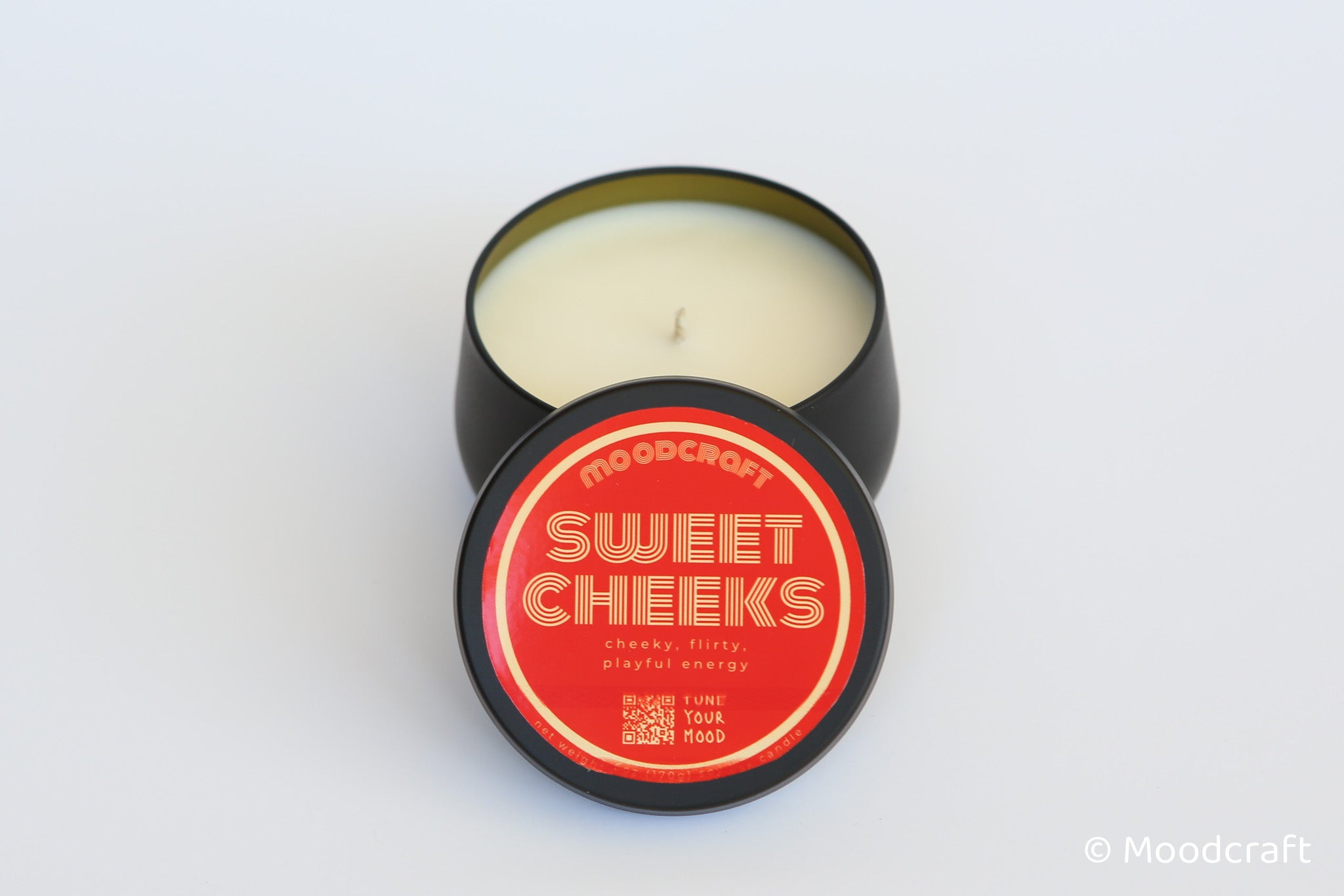 Moodcraft 'Sweet Cheeks' candle in a black tin with red lid on a white background