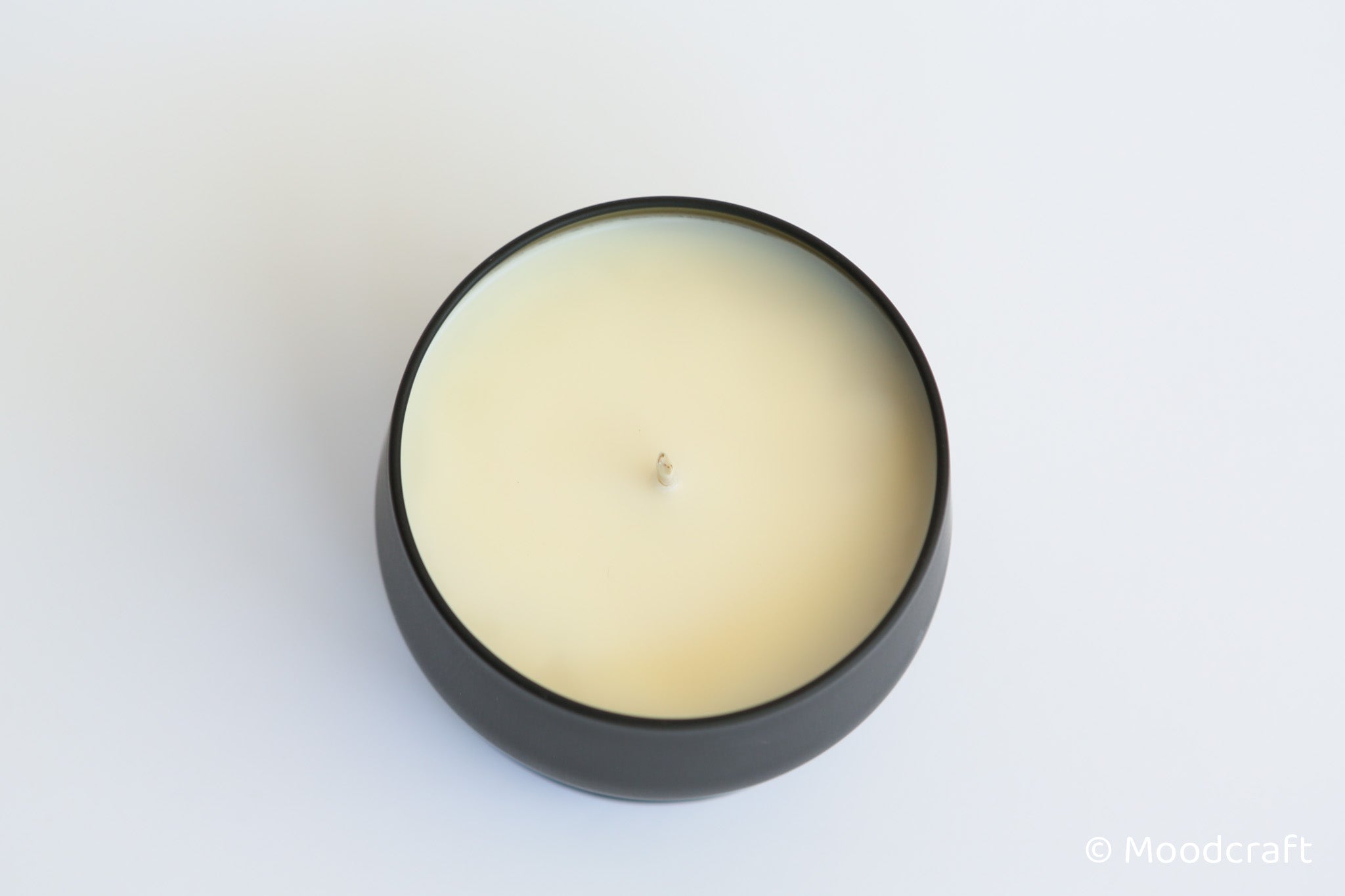 Round candle in a black holder on a white background