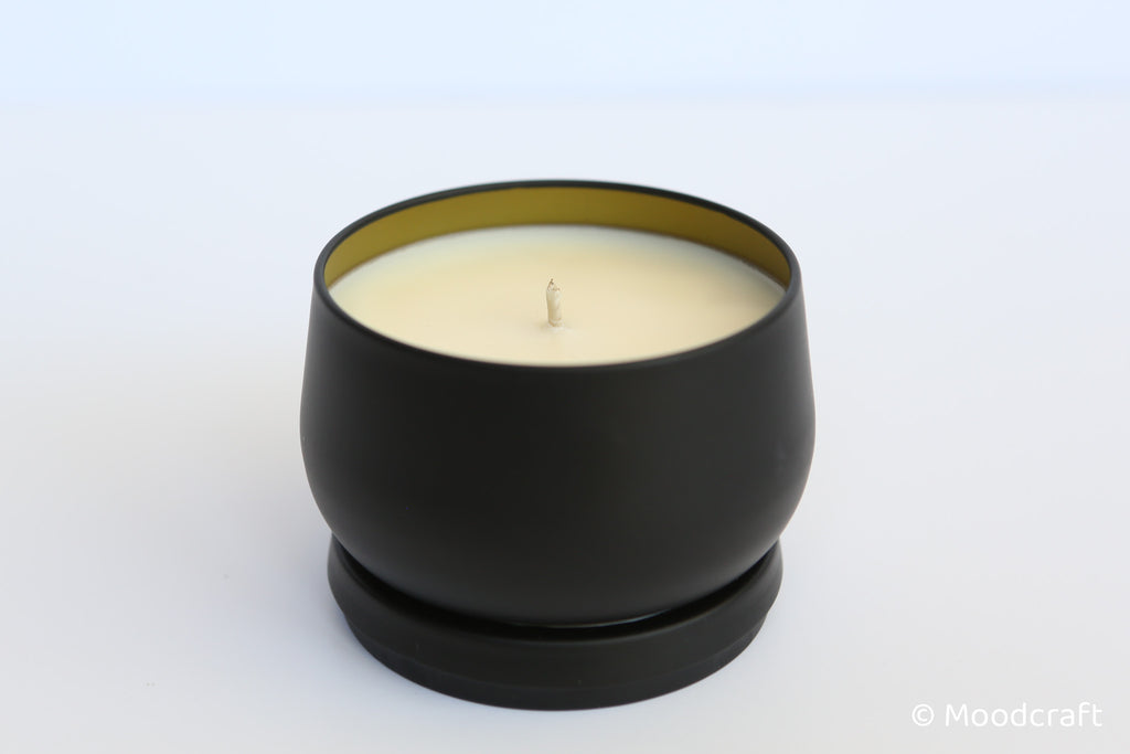 Black candle holder with a white candle on a light gray background