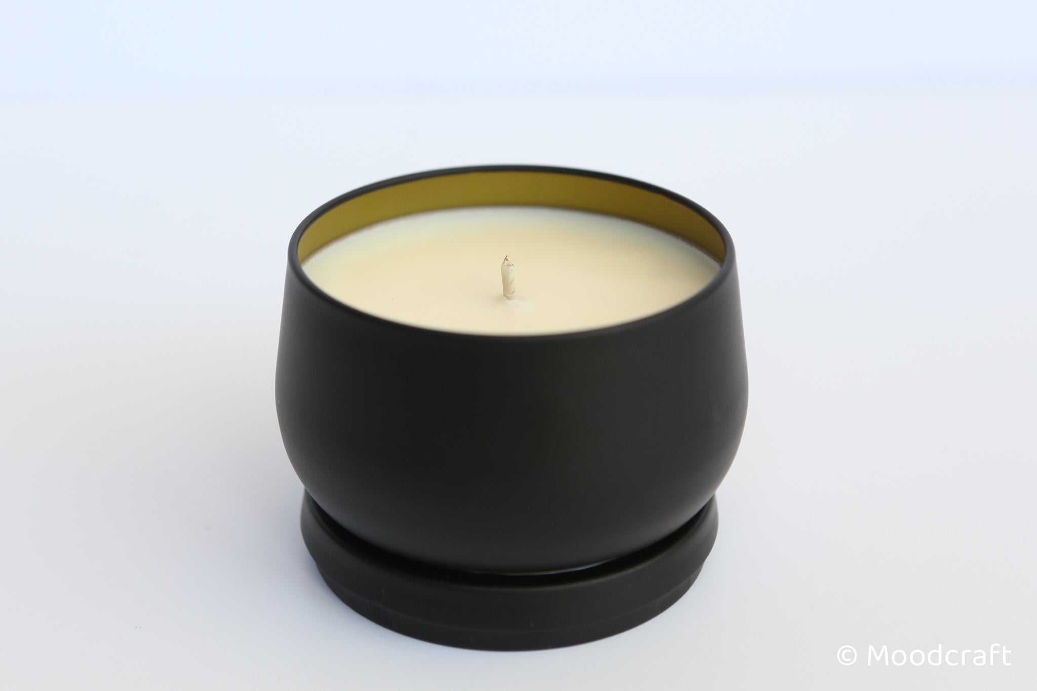 Black candle holder with a white candle on a light gray background