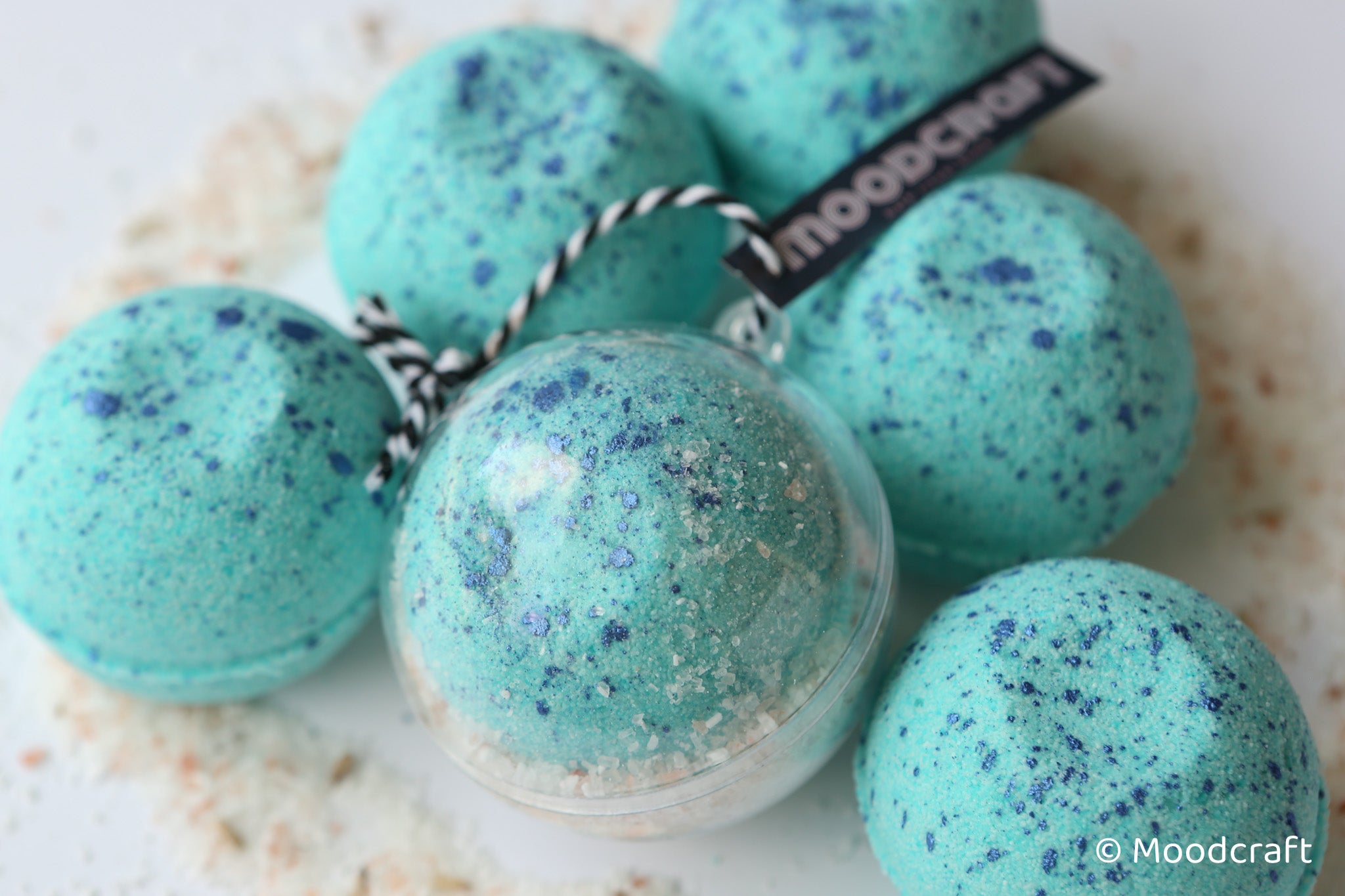 Turquoise bath bombs with speckles and a visible 'Moodcraft' label on a light background.
