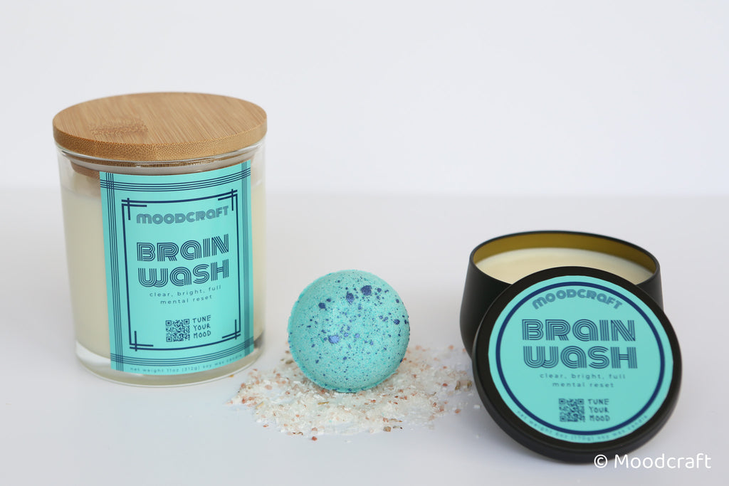 Two candles labeled 'Moodcraft Brain Wash' with a bath bomb on a white background