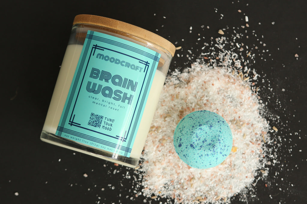 Bath bomb labeled 'Brain Wash' next to a jar with a similar label on a dark surface.